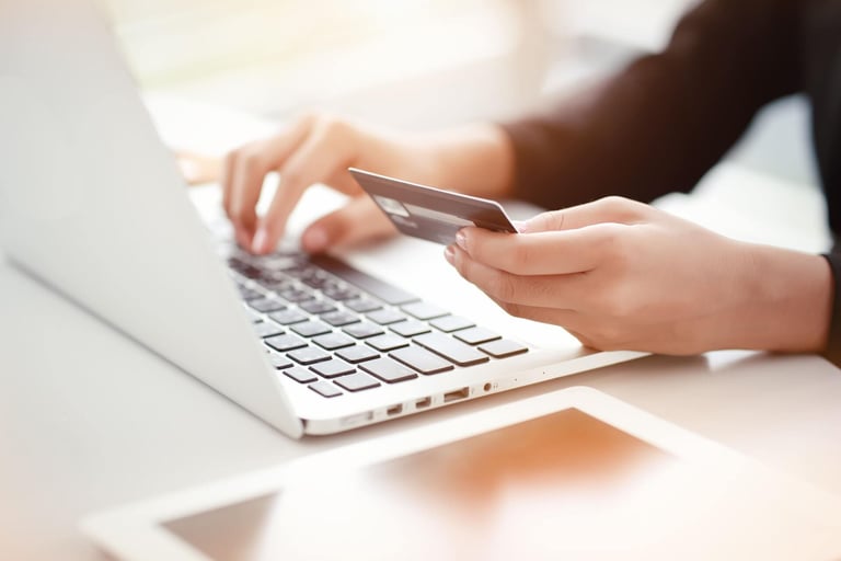 Pessoa fazendo contestação de compra pelo notebook com cartão de crédito na mão. 