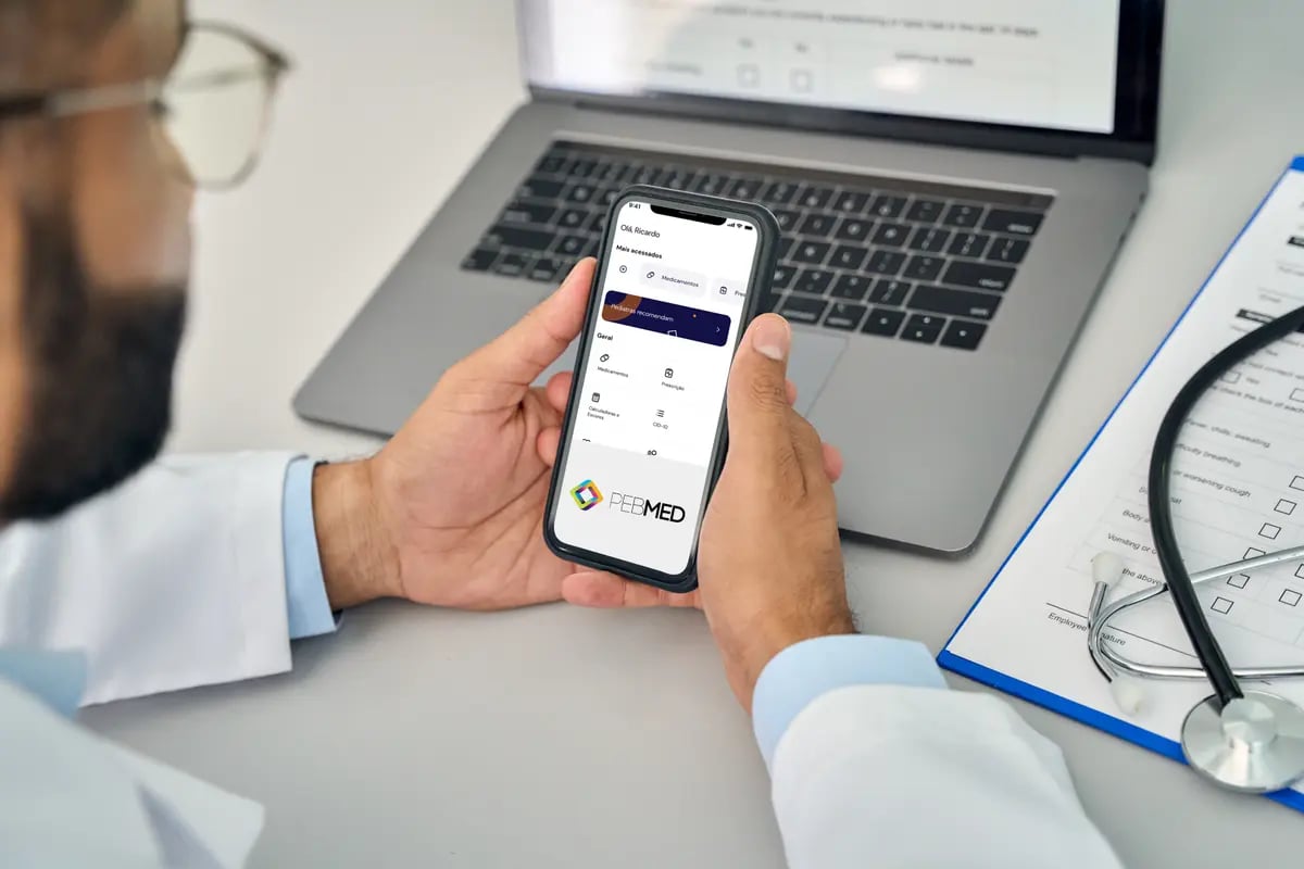 médico segurando celular e vendo a tela de aplicativo da PEBMED