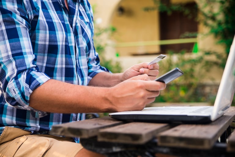 homem segurando um celular e um cartão de crédito fazendo um pagamento online