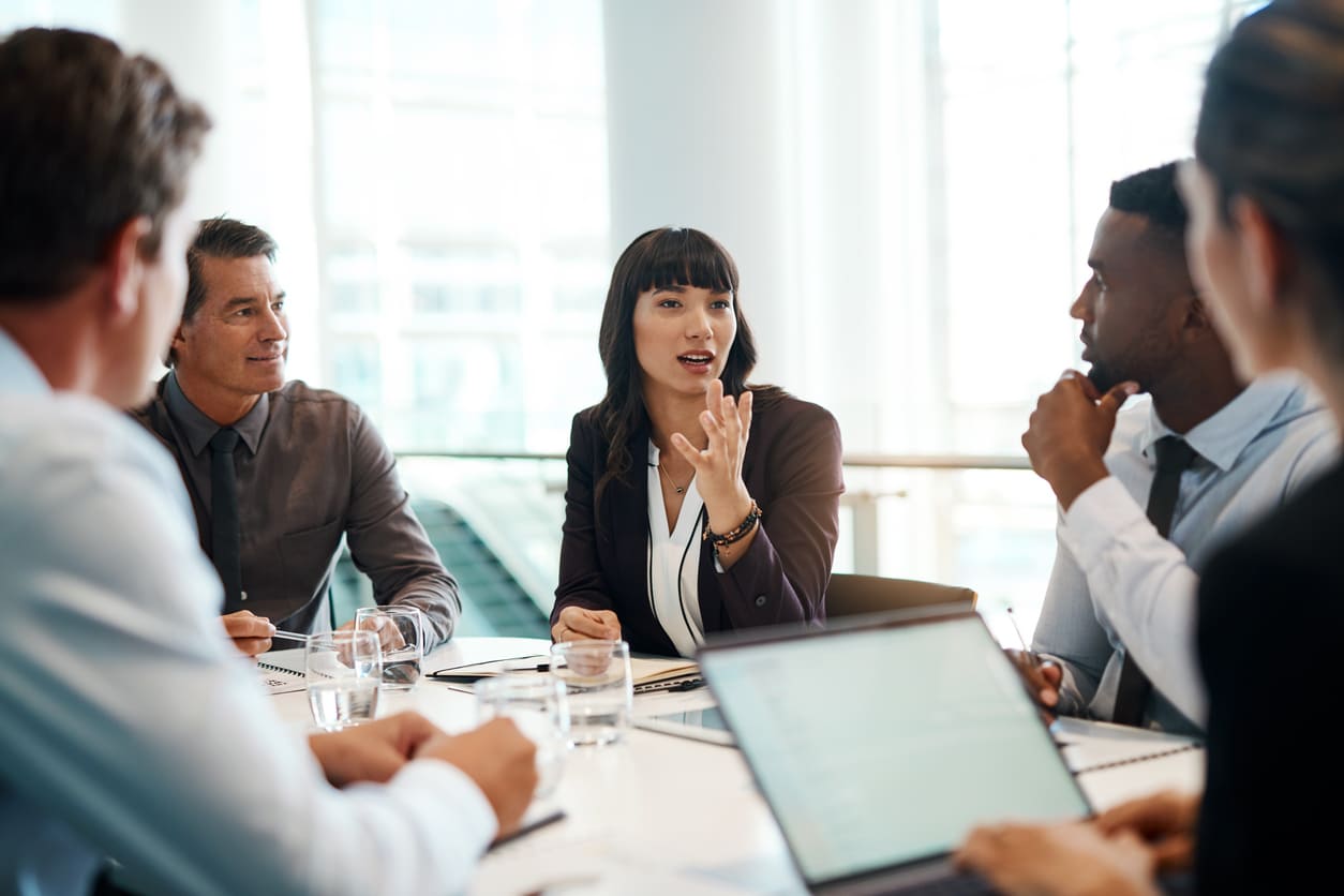 Reunião de negócios com profissionais discutindo estratégias em ambiente corporativo moderno, com foco em liderança e trabalho em equipe.